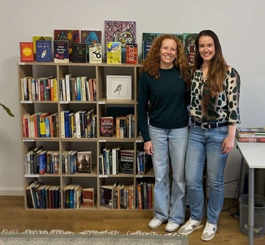 Mikaela (left) and Kara in front of the bookshelves